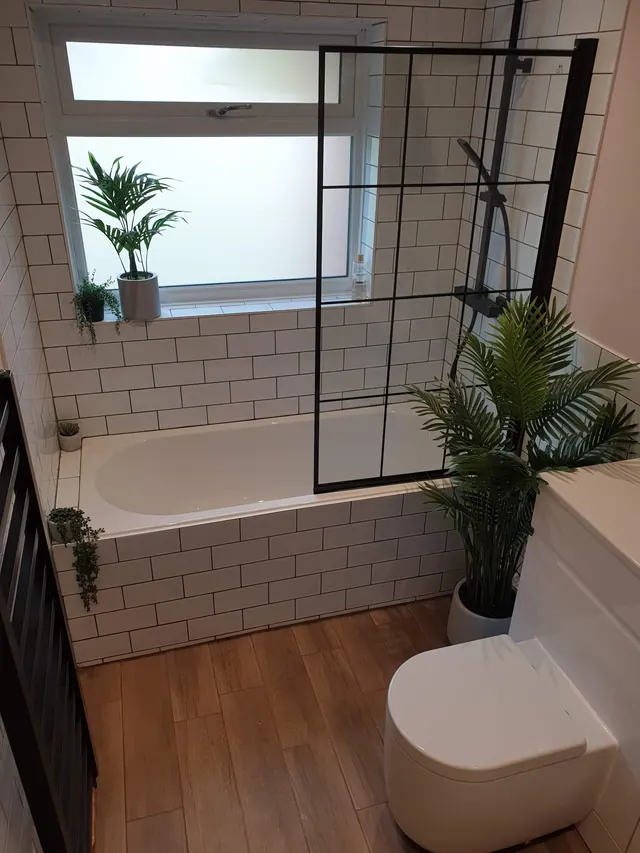Finished bathroom with black framed bath screen and white metro tiles