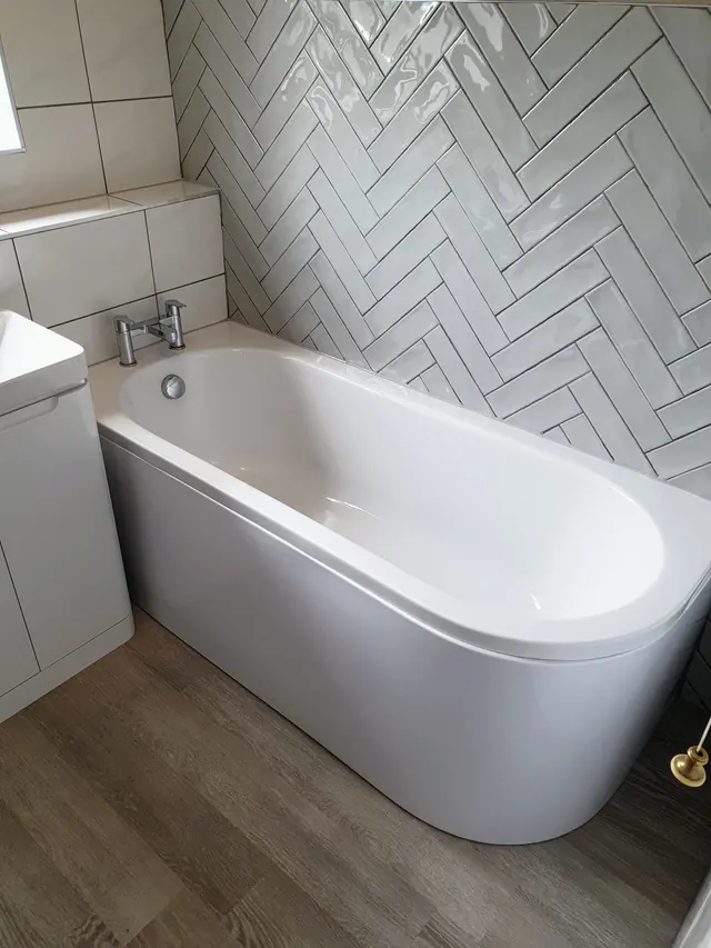 Completed bath installation with pale herringbone wall tiles