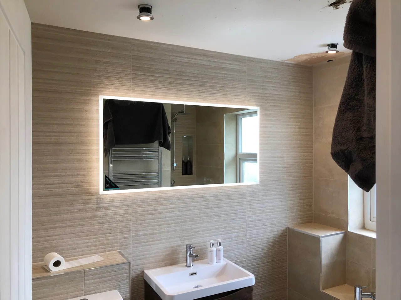 Contemporary completed bathroom with illuminated mirror and stone-effect tiling